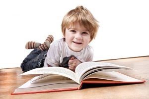 15209703 - young child laying on a wooden floor reading a book