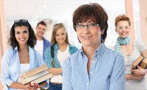 37664104 - portrait of happy senior female teacher with group of students in background.